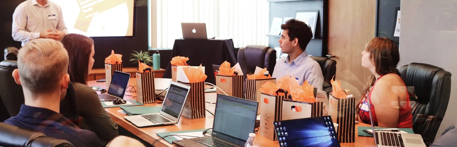 A team around a boardroom table reviewing work on laptops