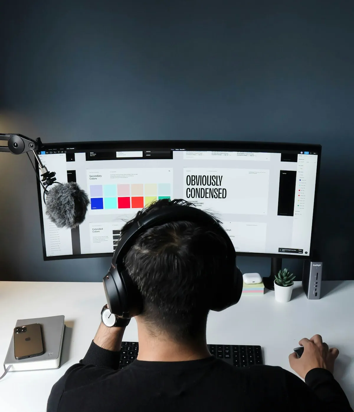 A designer at a wide monitor showing a colour ramp beside a type specimen