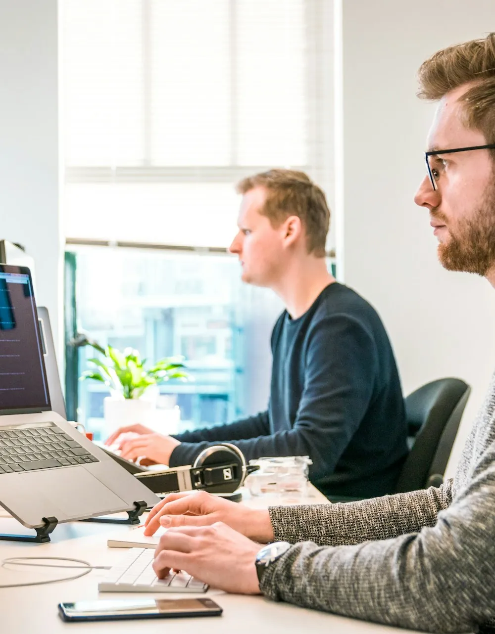 Two engineers working together at a dual-screen workstation