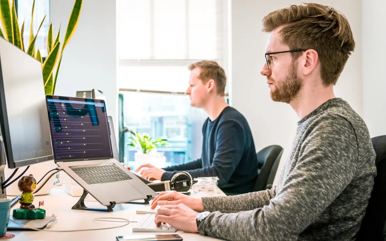 Two engineers working together at a dual-screen workstation