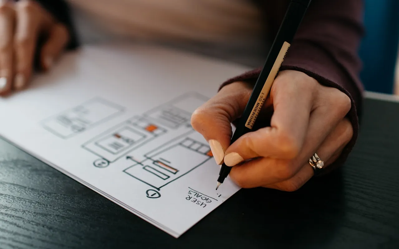 A hand sketching an interface wireframe, with states marked in orange