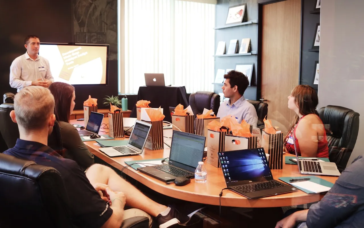 A team around a boardroom table reviewing work on laptops