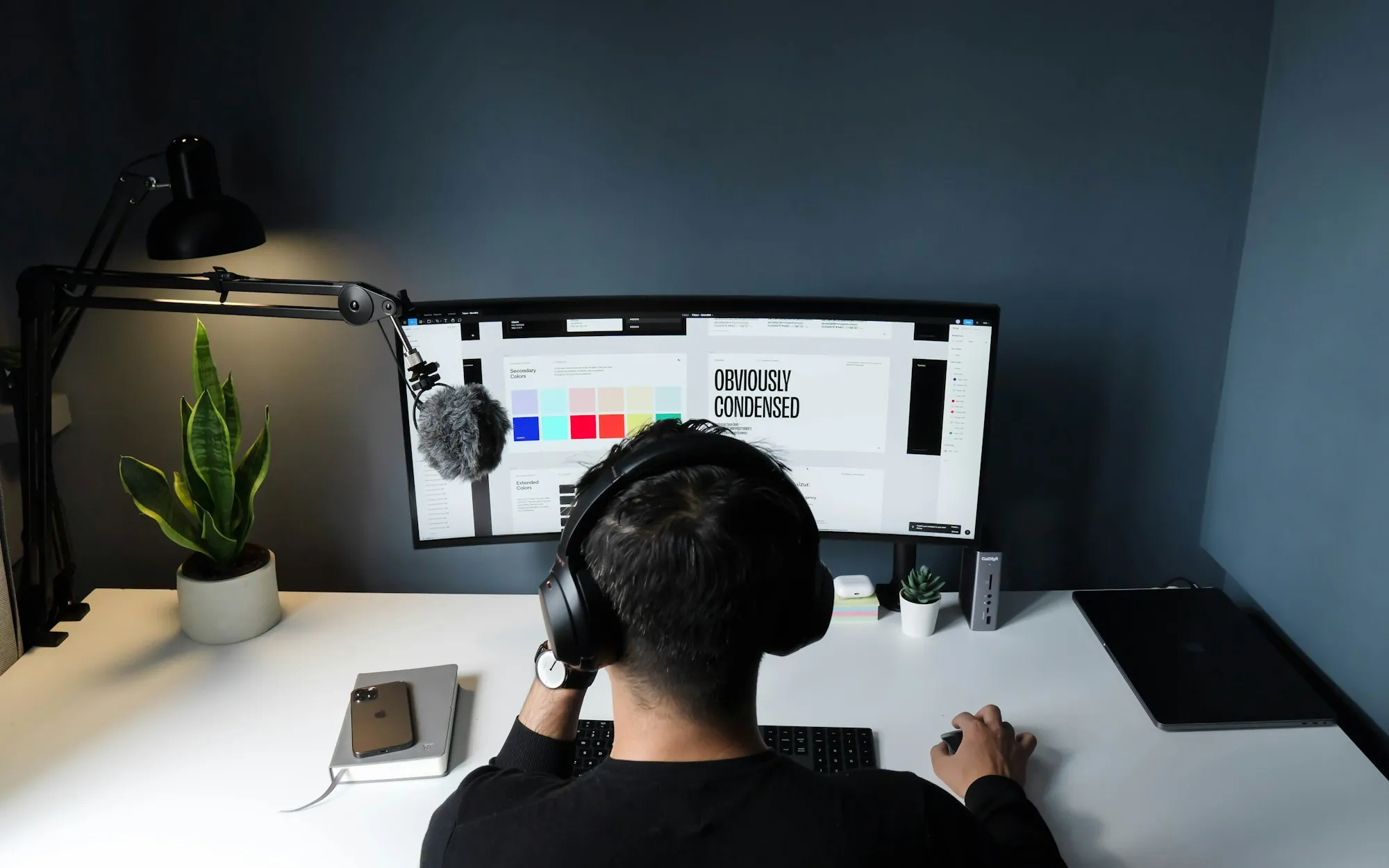 A designer at a wide monitor showing a colour ramp beside a type specimen