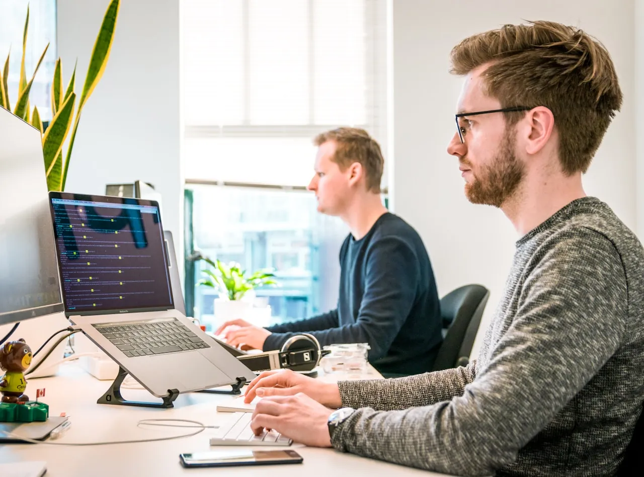 Two engineers working together at a dual-screen workstation