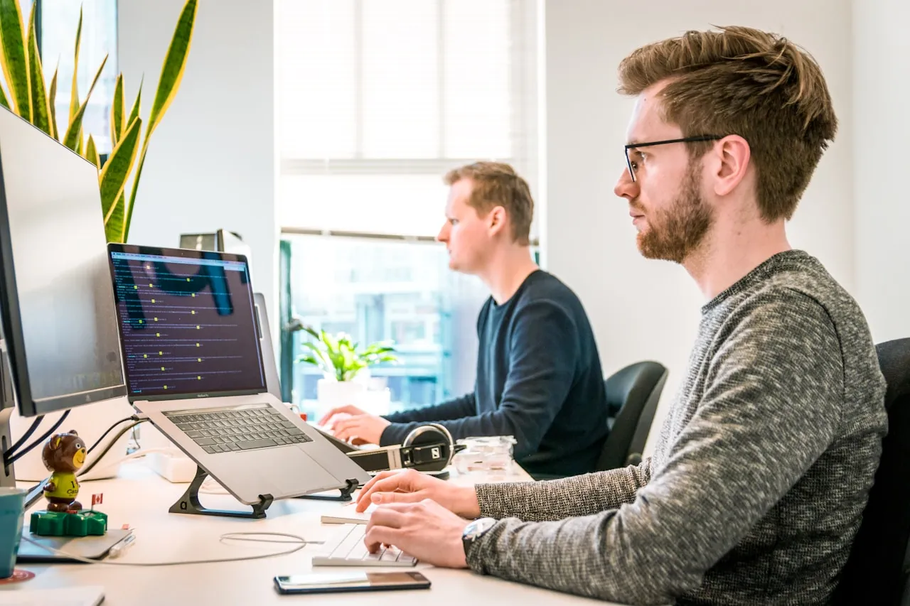 Two engineers working together at a dual-screen workstation