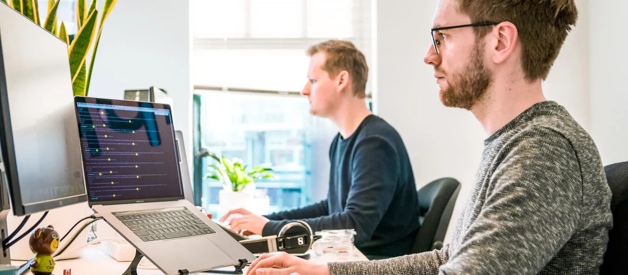 Two engineers working together at a dual-screen workstation