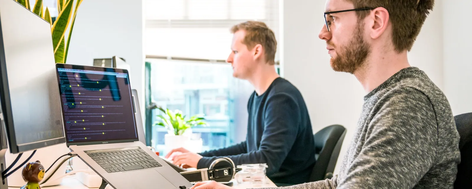Two engineers working together at a dual-screen workstation